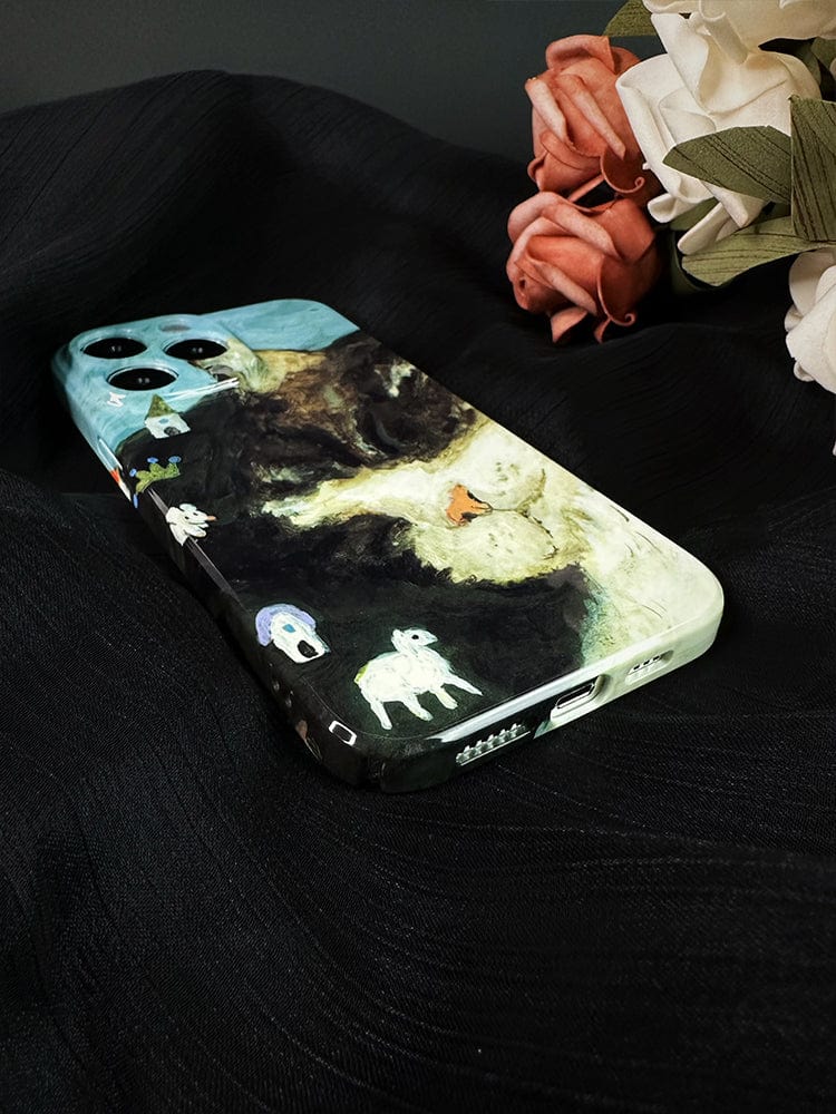 A smartphone adorned with the Whimsical Cat Dream iPhone 16 Pro Max Case, showcasing an artistic and playful design, rests on a textured black fabric. The case features small, scattered drawings of elephants, a sheep, and a house against a serene mountain and sky backdrop. Nearby are white and pink paper flowers.