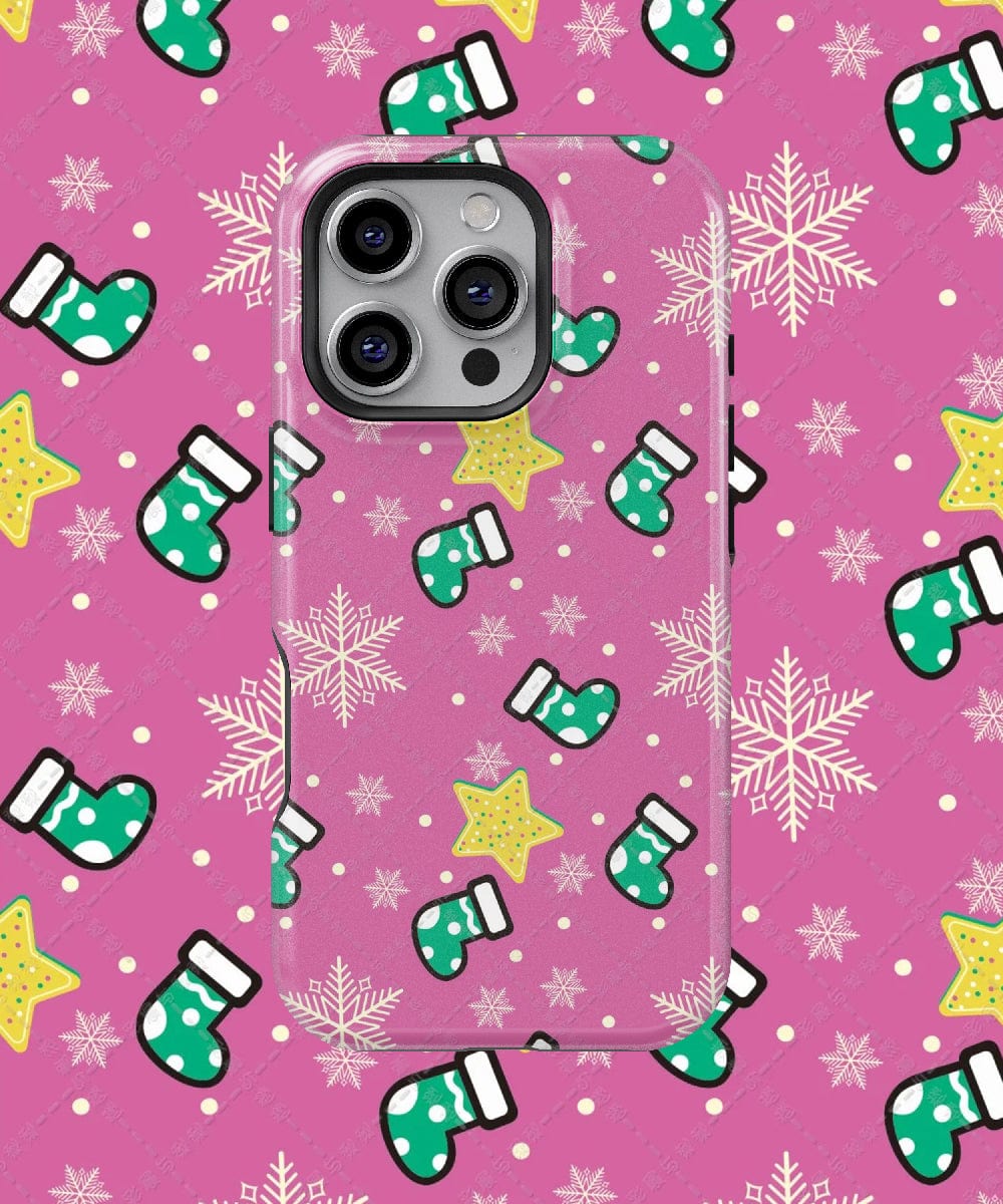 A vibrant smartphone is adorned in the Festive Stocking iPhone 16 Pro Max Case featuring a pink holiday design with green stockings, yellow stars, and white snowflakes. Resting on a matching background, this MagSafe-compatible case provides dual-layer protection while showcasing your device's festive cheer.