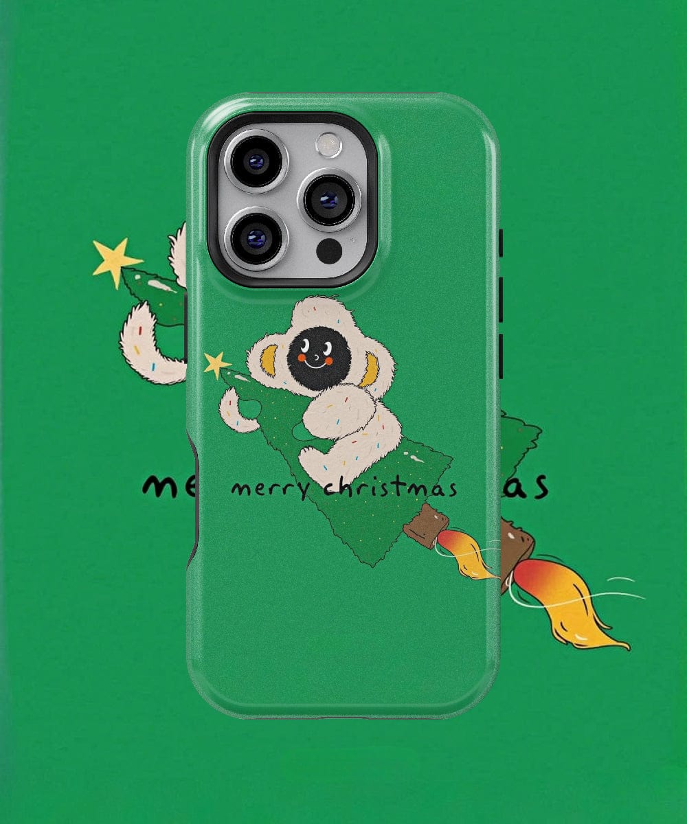 This iPhone 16 Pro Max case, compatible with MagSafe, presents a festive monkey design in a green holiday theme. The merry Christmas monkey character is depicted wearing a hood and holding an ornament-adorned tree branch, accompanied by the text "Merry Christmas.