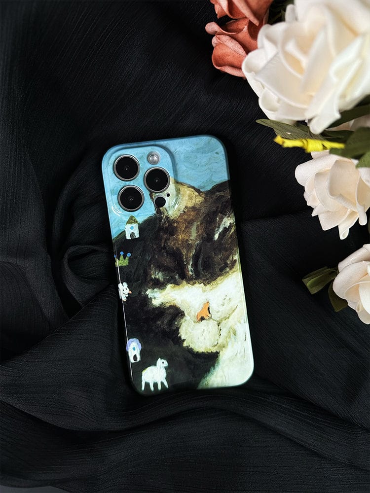 A Whimsical Cat Dream iPhone 16 Pro Max Case, boasting an artistic and playful design with a whimsical landscape of hills, houses, sheep, and a serene sky, rests on a black fabric. White and pink flowers are placed next to the phone.