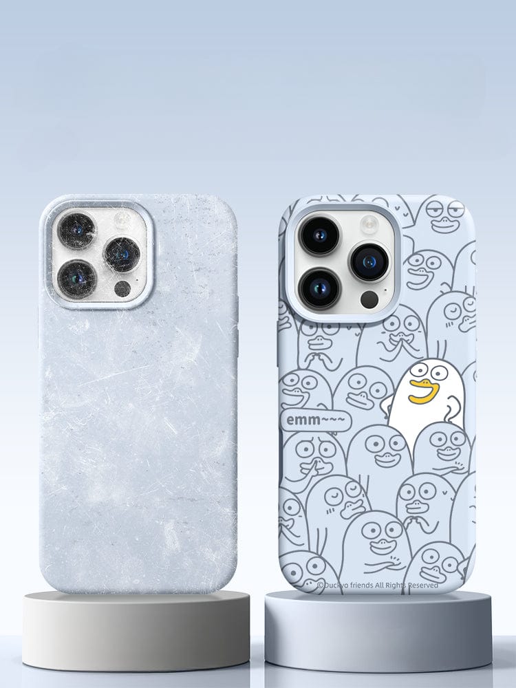 Two smartphones in cases stand on cylindrical platforms. The left phone case has a marble texture, while the right phone sports an iPhone 16 Pro Max Case featuring an Emm Duck cartoon design with a crowd pattern and an expression caption reading "emm~". Both cases offer full-coverage protection for your device.