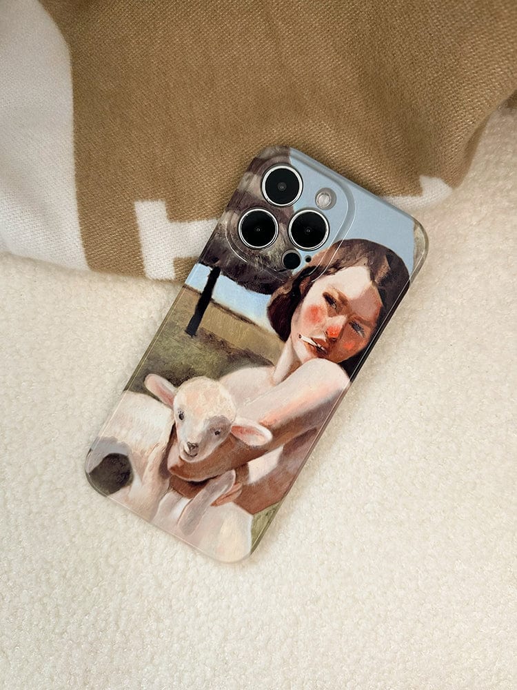 A phone with a Pastoral Art iPhone 16 Pro Max Case - Vintage-Inspired Design with a Modern Twist, featuring a painting of a woman holding a lamb, is placed on a soft, light-colored surface with parts of beige and white fabric visible in the background.