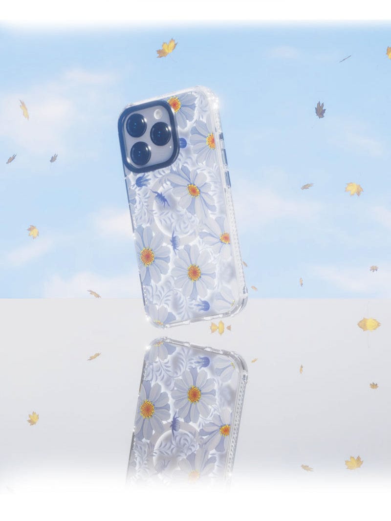 A Floral MagSafe iPhone 16 Pro Max Case with a 3D flower design is displayed against a backdrop of a blue sky adorned with yellow and white flowers. The phone's reflection can be seen below, showcasing its shockproof TPU + PC protective shell.