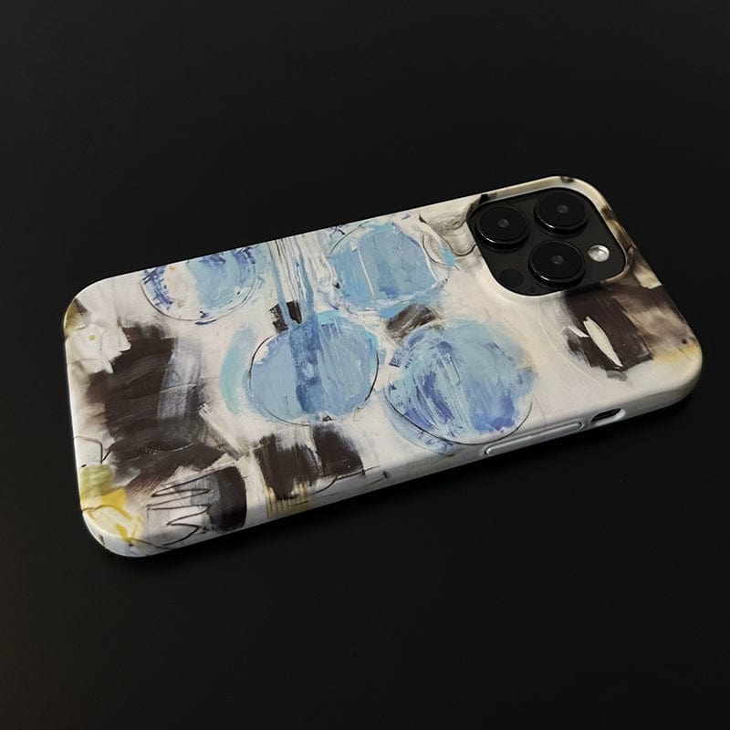 An Abstract Blue Circles iPhone 16 Pro Max Case - Modern Art-Inspired Design with Full Protection lies on a black surface, showcasing its unique abstract design of blue circles and black and brown brushstrokes. The phone's triple camera setup is visible in the upper right corner of the case.