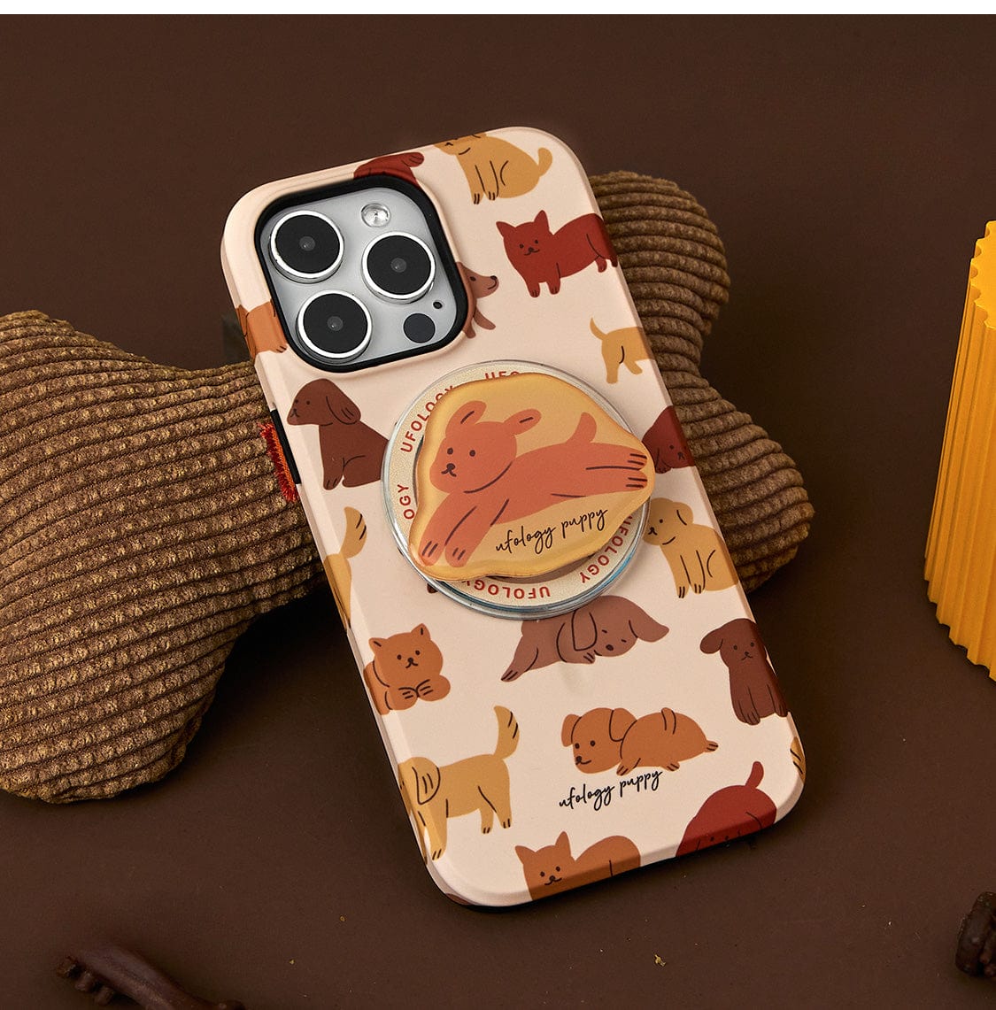 The Puppy Playtime MagSafe iPhone 16 Pro Max Case features illustrations of brown and orange dogs, complete with a matching phone grip depicting a dog laying down, perfect for fabric surfaces.