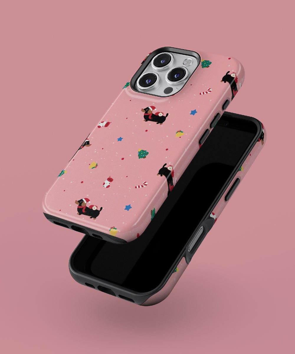 Explore the Christmas Dachshund iPhone 16 Pro Max Case – Festive Dog Design, featuring a delightful pink phone case adorned with cute holiday patterns of dachshunds, candy canes, and stars. This MagSafe compatible case offers durable dual-layer protection, making it an ideal accessory for your smartphone against a cheerful pink background.