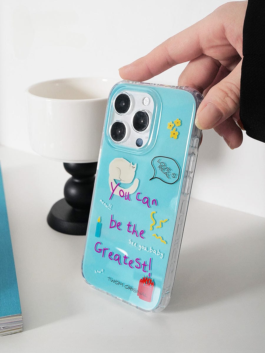 A person holds a "You Can Be the Greatest" iPhone 16 Pro Max case, showcasing a fun motivational design with optimistic text and illustrations set against a light blue background. The playful all-inclusive protective cover features a 3D effect, offering excellent protection for the phone's camera lenses.