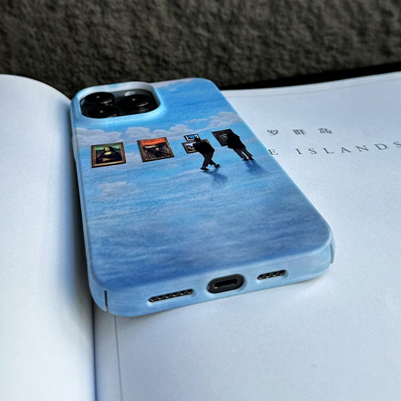 A smartphone adorned with the Surreal Art Gallery iPhone 16 Pro Max Case—Dreamy and Protective, showcasing artwork of two silhouetted figures observing framed pictures. The vibrant blue case is placed on an open book displaying text with unreadable Japanese characters, against a textured gray backdrop.