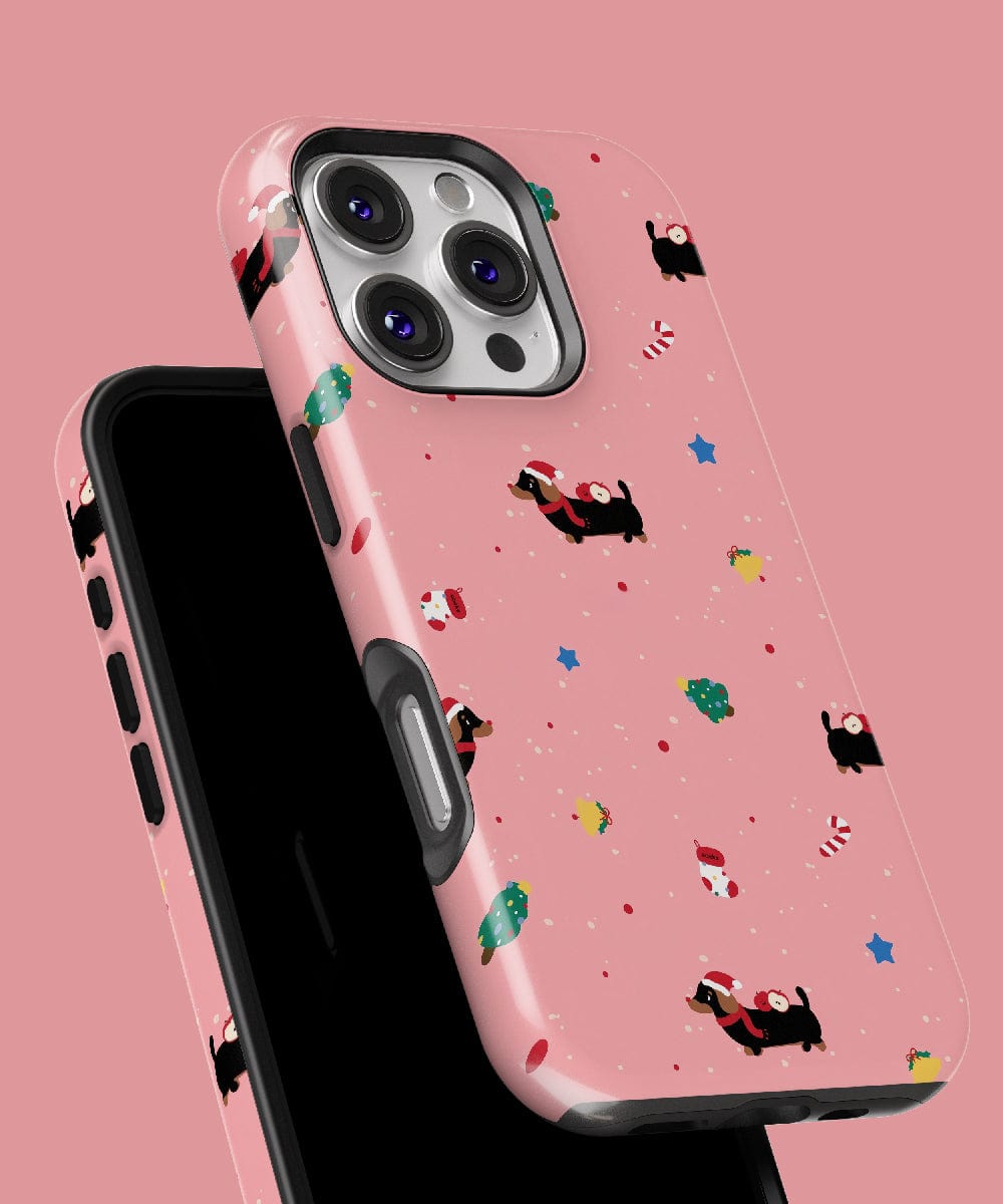 The Christmas Dachshund iPhone 16 Pro Max Case, featuring a cute holiday pattern with Santas and trees on a pink background, provides durable dual-layer protection and is MagSafe compatible.